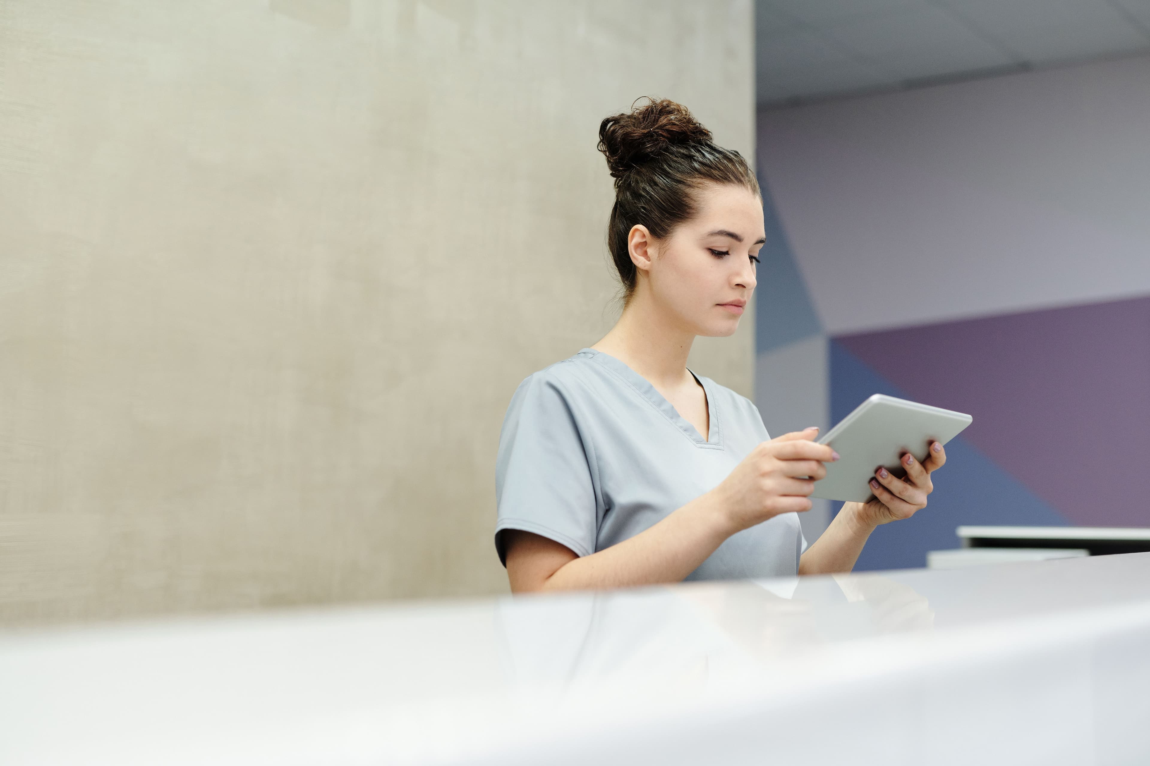 Clinic staff member reviewing patient information on a tablet at the front desk