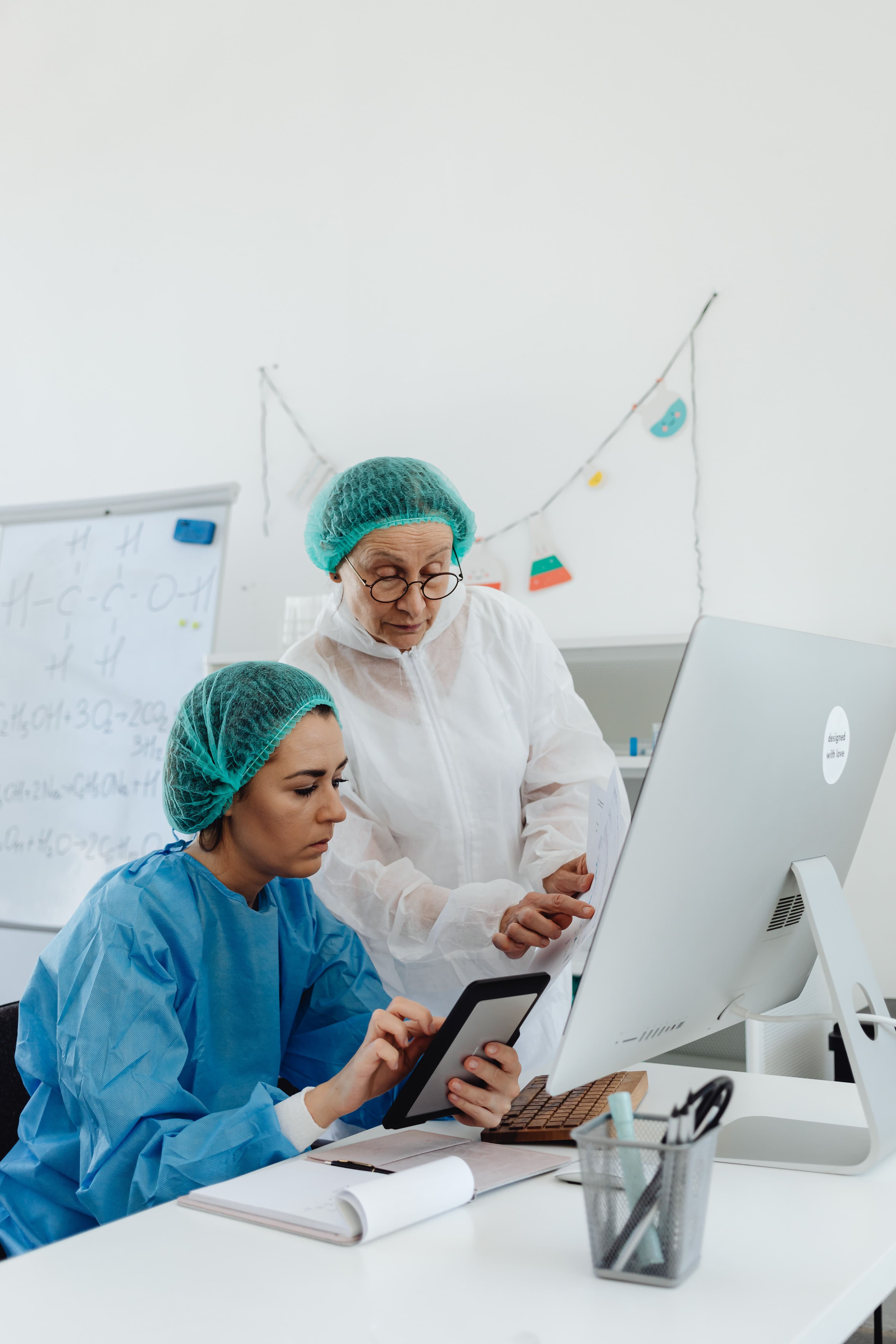 Clinical lab staff reviewing specimen data on a tablet and monitor